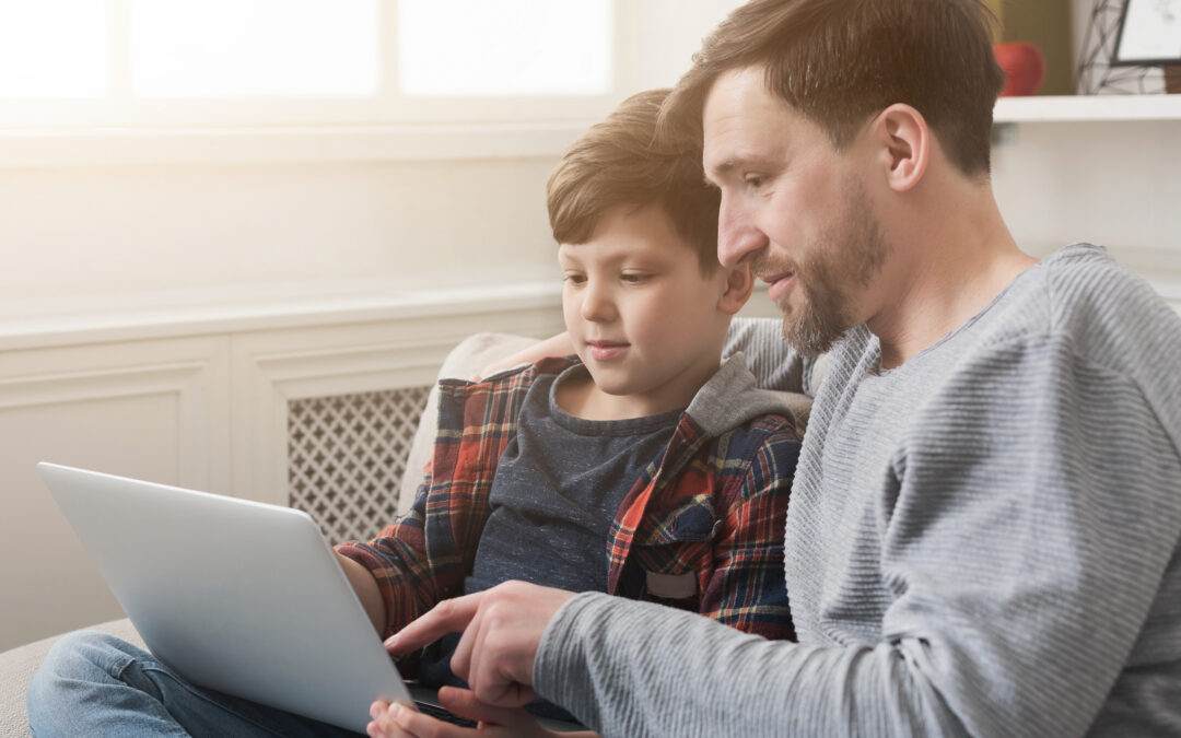 Happy father and son using laptop at home